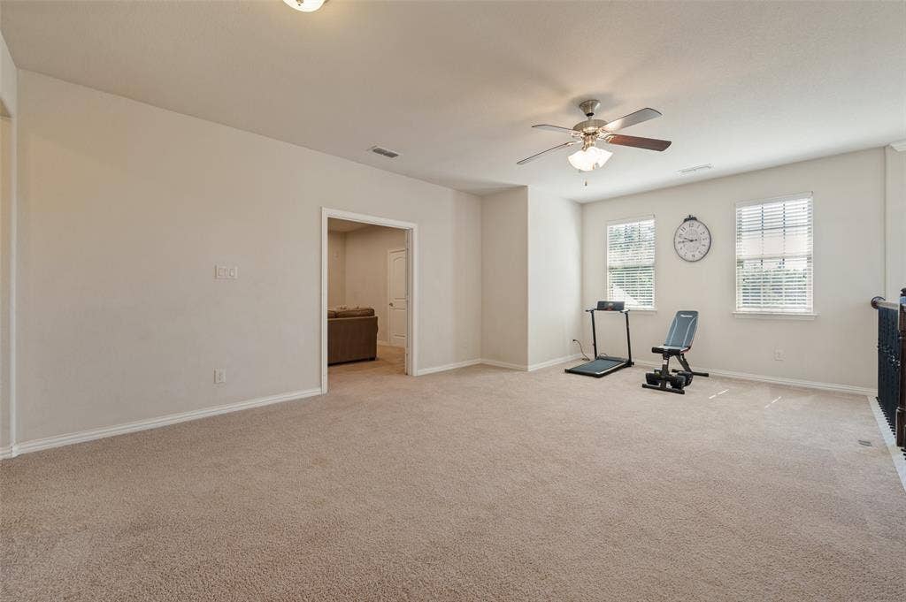 741 Darian Drive, Prosper, TX 75078 Spacious carpeted room featuring a ceiling fan with integrated lighting, two windows with blinds, and an open doorway leading to another room