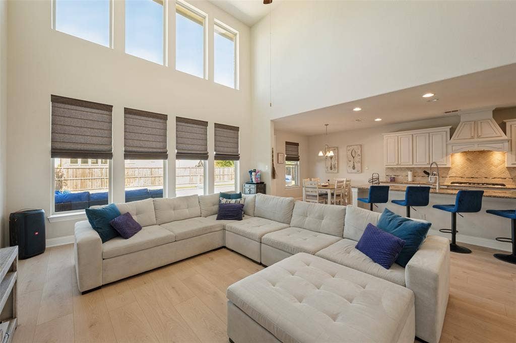 741 Darian Drive, Prosper, TX 75078 High ceilings with upper transom windows, light wood-finish flooring, recessed lighting, and a kitchen featuring a large island with bar seating