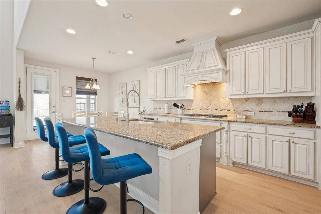 741 Darian Drive, Prosper, TX 75078 Kitchen featuring a center island with a stone countertop, white cabinetry, tile backsplash, and wood-finish flooring