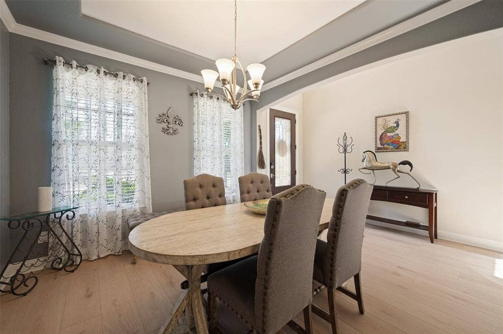741 Darian Drive, Prosper, TX 75078 Elegant dining room showcasing a wood-finish oval table, upholstered dining chairs with nailhead detailing, and a contemporary chandelier