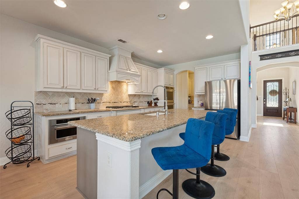 741 Darian Drive, Prosper, TX 75078 Kitchen featuring white cabinetry, granite countertops, stainless steel appliances, a tile backsplash, and wood-finish flooring