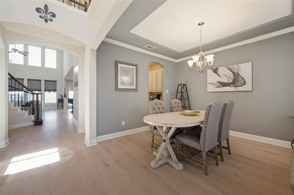 741 Darian Drive, Prosper, TX 75078 Formal dining area featuring a tray ceiling with crown molding, chandelier, and wood-finish flooring