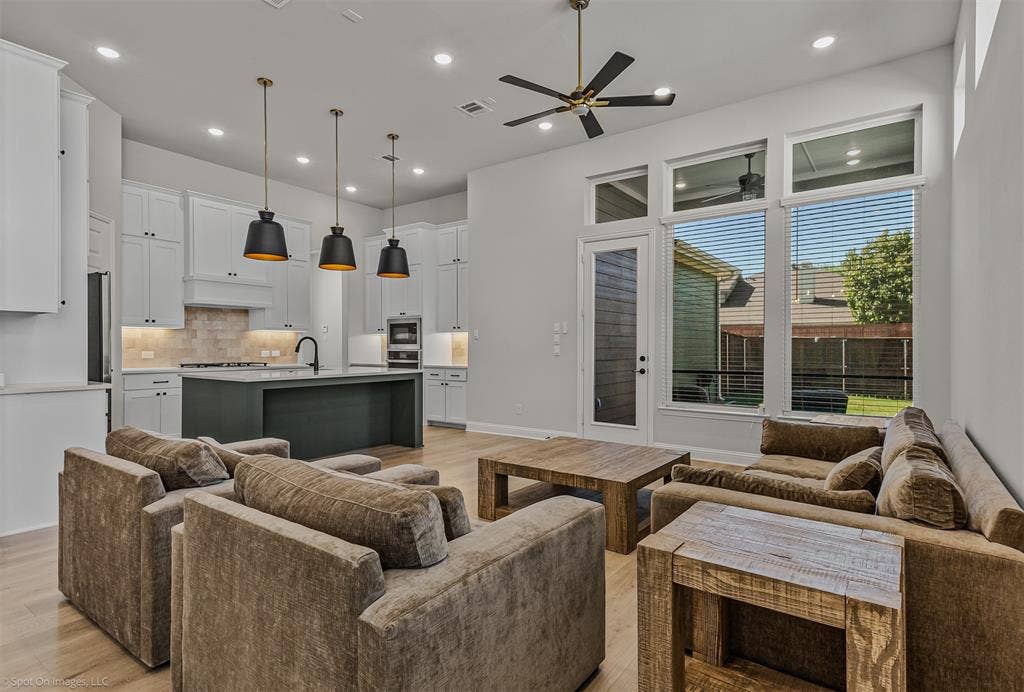 2601 Lafayette Drive, Rowlett, TX 75088 Open concept living area with light wood-finish flooring, recessed lighting, and a dark-toned kitchen island with a single basin sink