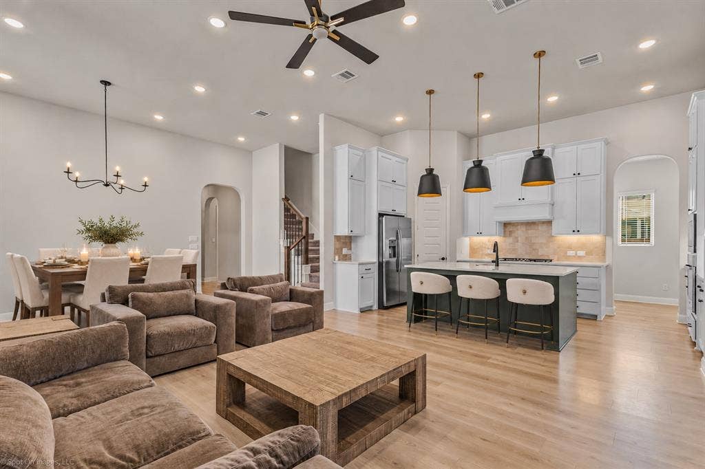 2601 Lafayette Drive, Rowlett, TX 75088 Open-concept living space featuring wood-finish flooring, a contemporary kitchen island with pendant lighting, white shaker cabinetry, and a dining area with a chandelier