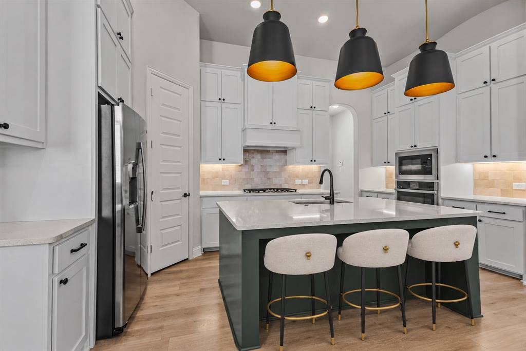 2601 Lafayette Drive, Rowlett, TX 75088 Kitchen featuring light wood-finish flooring, white cabinetry, integrated stainless steel appliances, a center island with a light-toned countertop, and recessed lighting