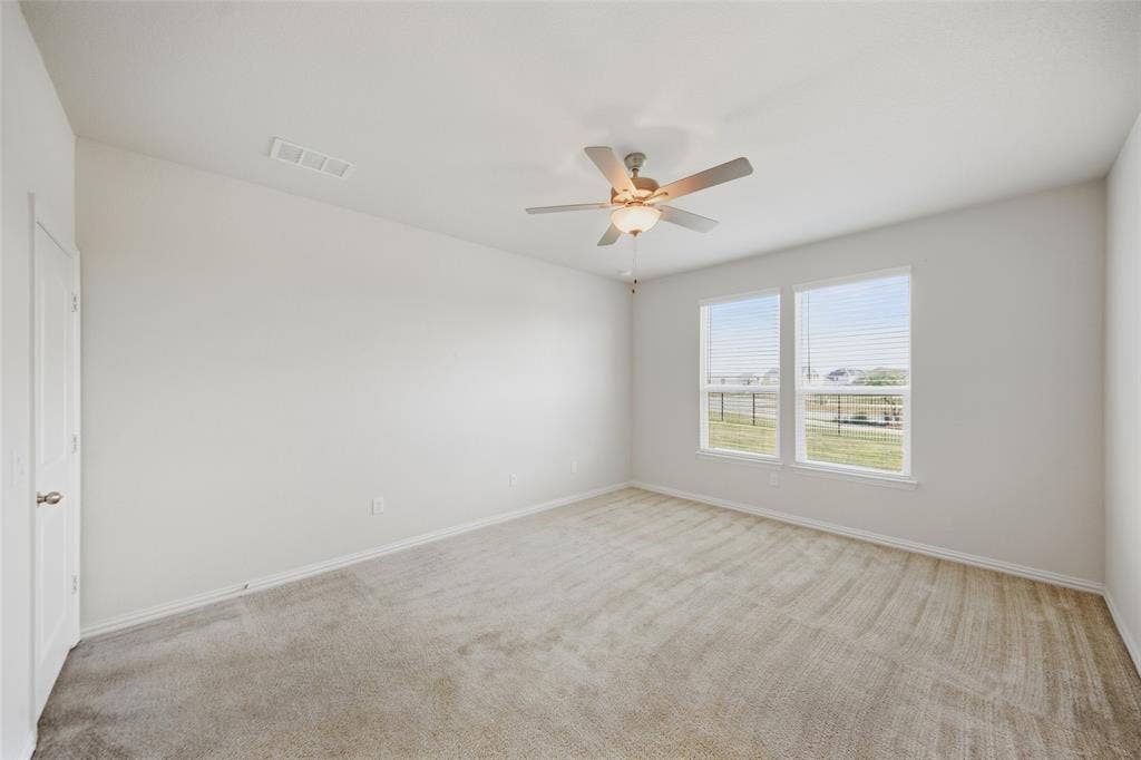 1805 Nelson Street, Anna, TX 75409 Spacious room featuring neutral carpeting, two large windows with blinds, a ceiling fan with integrated lighting, and a white paneled door