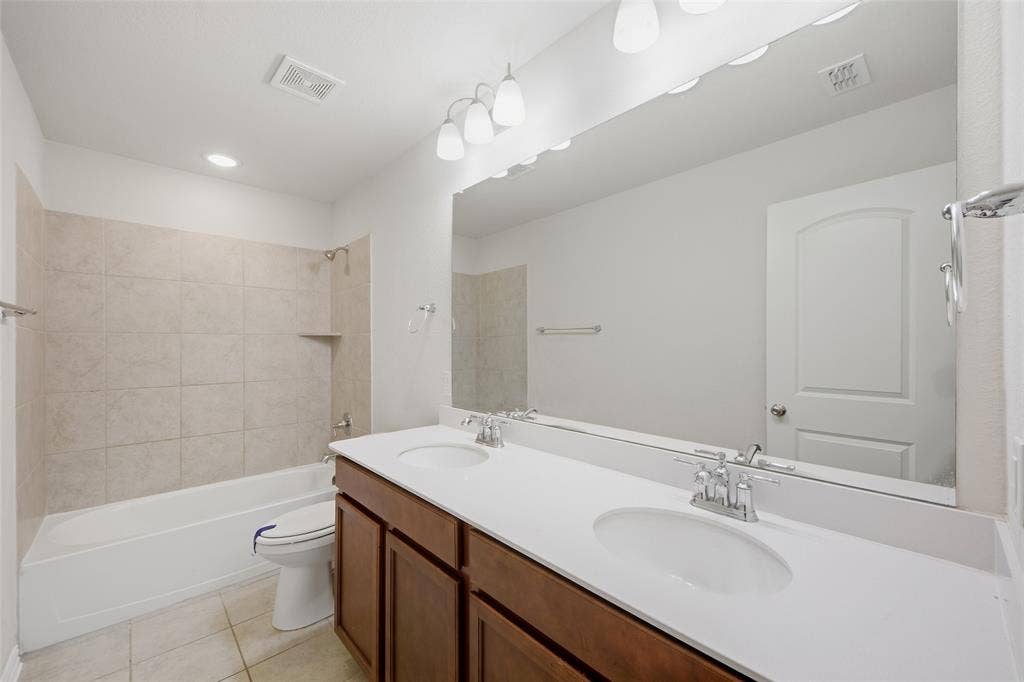 1805 Nelson Street, Anna, TX 75409 Double vanity with integrated sinks, a large wall-mounted mirror, and a combination tub and shower with tile surround