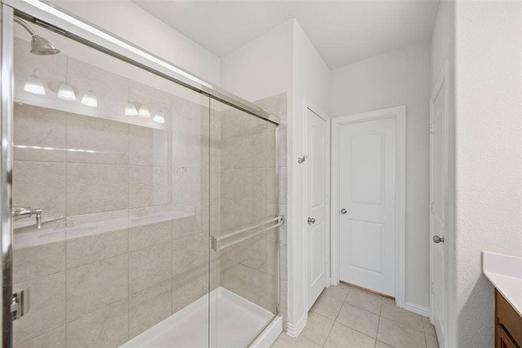 1805 Nelson Street, Anna, TX 75409 Glass-enclosed shower with a tiled surround, built-in ledge, and brushed nickel showerhead
