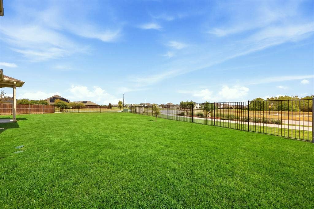 1805 Nelson Street, Anna, TX 75409 Expansive lawn with a black metal fence and a wood-panel fence