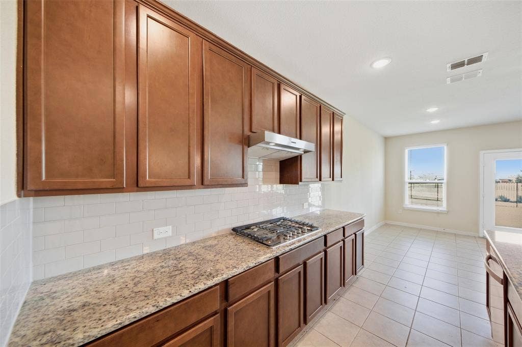 1805 Nelson Street, Anna, TX 75409 Kitchen featuring rich wood cabinetry, patterned stone countertops, a gas cooktop, subway tile backsplash, and recessed lighting