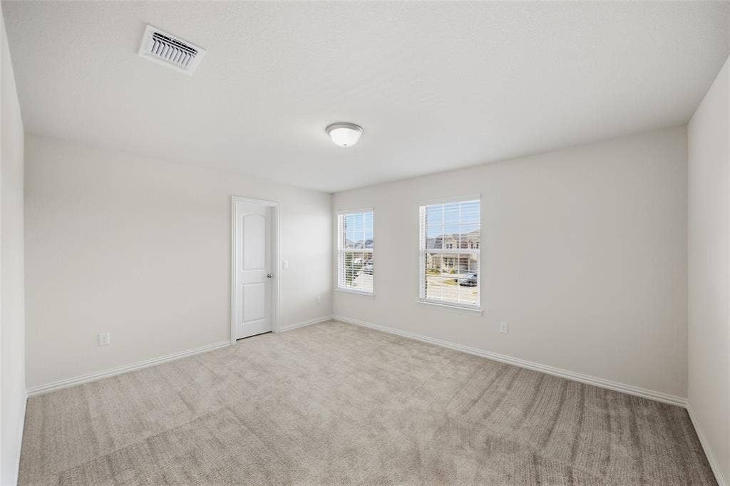 1805 Nelson Street, Anna, TX 75409 Neutral wall paint with carpet flooring, two windows with blinds, and an overhead flush-mount light fixture