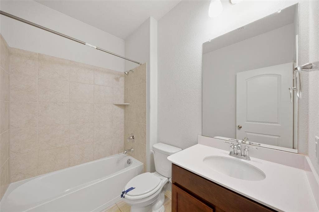 1805 Nelson Street, Anna, TX 75409 White bathtub with tiled surround, single vanity with integrated sink, white countertop, and dark wood-finish cabinetry