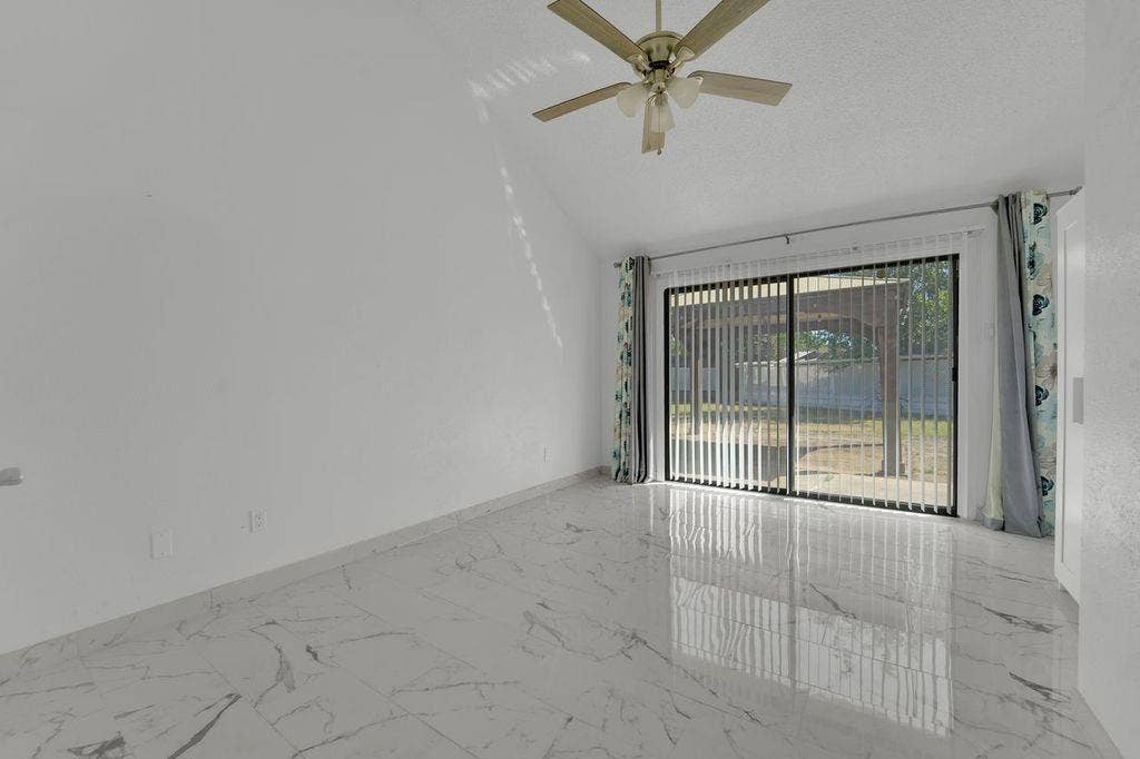High ceilings with a ceiling fan, sliding glass door with vertical blinds, and polished tile flooring