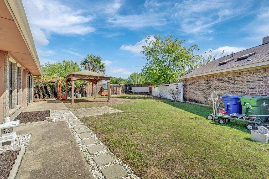 Backyard with a wooden gazebo, concrete patio, stepping stone pathway, and a privacy fence