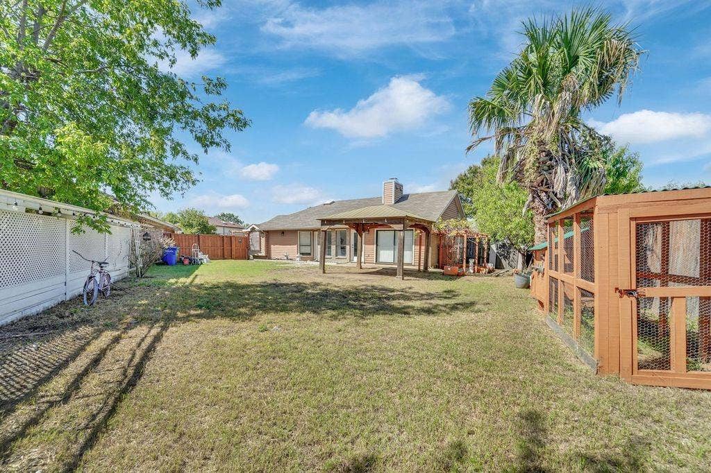 Expansive backyard featuring a covered patio, privacy fencing, and a detached wooden structure