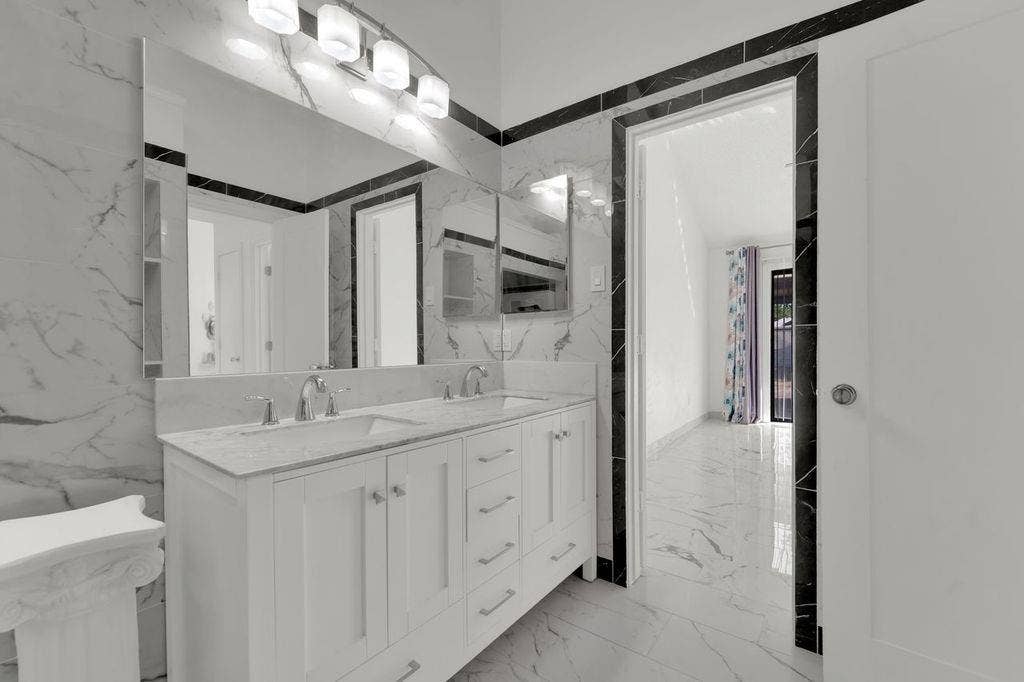 Dual vanity with undermount sinks and chrome fixtures, illuminated by a four-light fixture