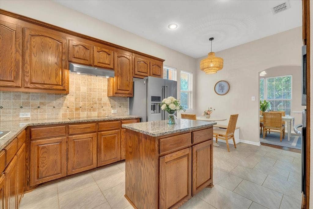5612 Hampshire Drive, McKinney, TX 75070 Kitchen featuring wood cabinetry, granite countertops, tile backsplash, and tile flooring