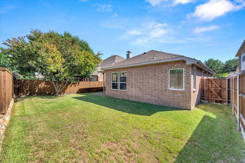 5612 Hampshire Drive, McKinney, TX 75070 Brick exterior with a shingled roof, featuring multiple windows and a privacy fence