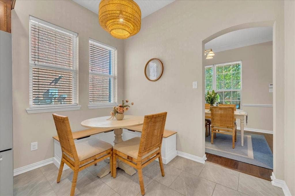 5612 Hampshire Drive, McKinney, TX 75070 Light-filled dining area featuring two windows with blinds, a built-in bench, and tile flooring