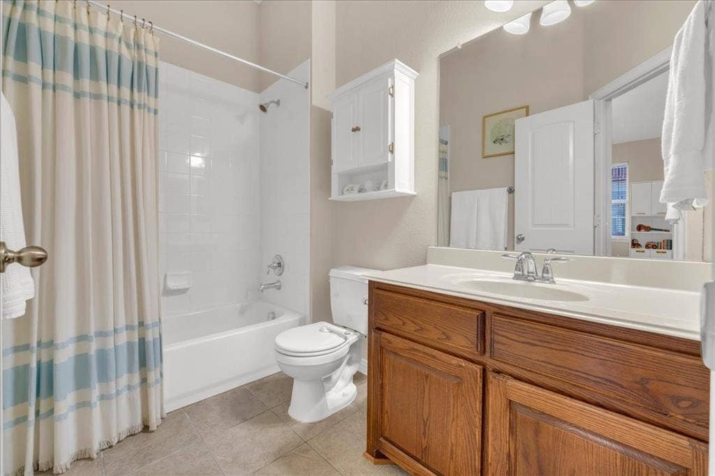 5612 Hampshire Drive, McKinney, TX 75070 Bathroom featuring a built-in tub with shower, wood-finish vanity with a single basin sink, and a wall-mounted storage cabinet