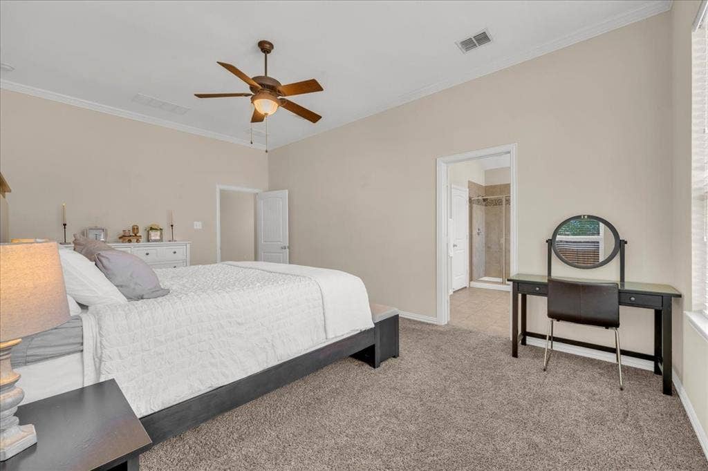 5612 Hampshire Drive, McKinney, TX 75070 Vaulted ceiling with crown molding, ceiling fan, carpet flooring, and an en-suite bathroom with a glass-enclosed shower