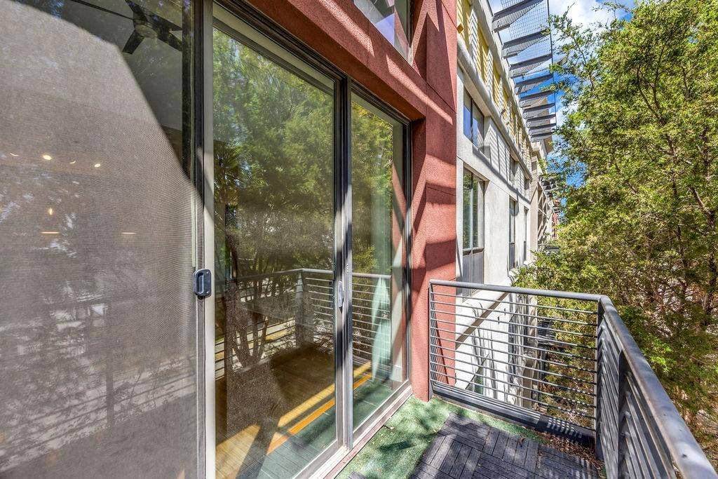 4605 Cedar Springs Road, #327, Dallas, TX 75219 Balcony featuring sliding glass doors, metal railings, and a partial faux turf surface