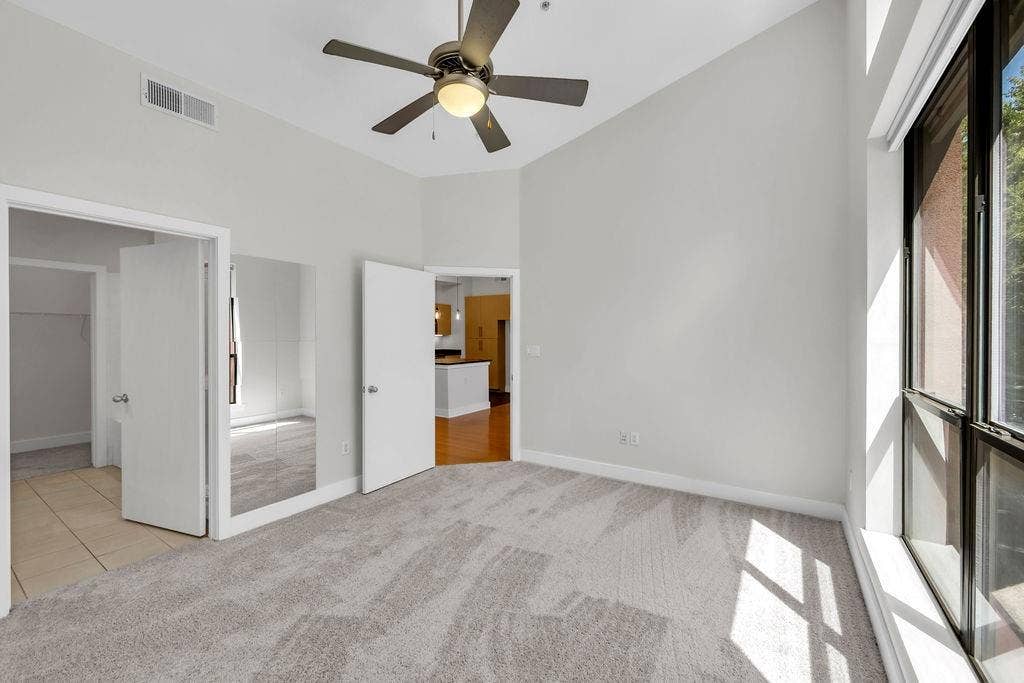 4605 Cedar Springs Road, #327, Dallas, TX 75219 Grey carpet flooring with a ceiling fan, vaulted ceiling, and large windows