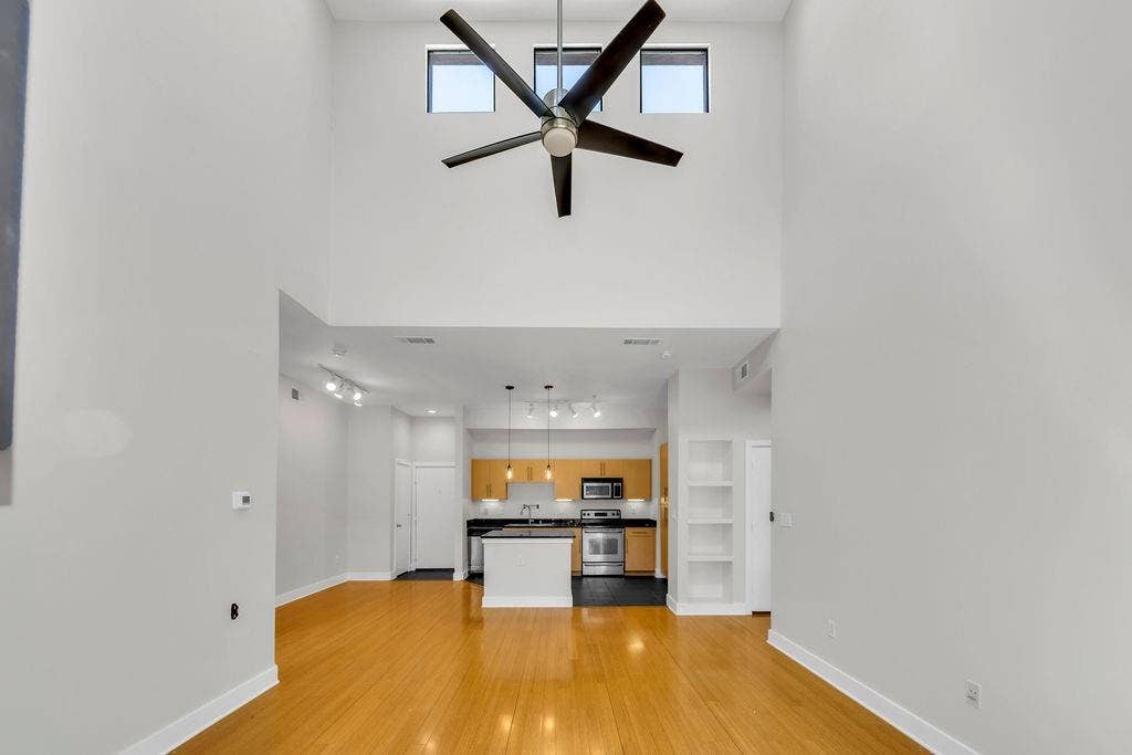 4605 Cedar Springs Road, #327, Dallas, TX 75219 Soaring ceilings with transom windows, wood-finish flooring, modern ceiling fan, built-in shelving, and contemporary kitchen with stainless steel appliances