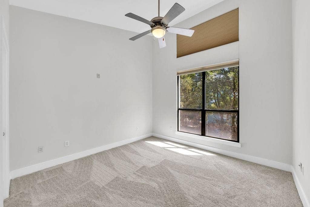 4605 Cedar Springs Road, #327, Dallas, TX 75219 Carpeted room featuring a ceiling fan, a large window, and a high transom window
