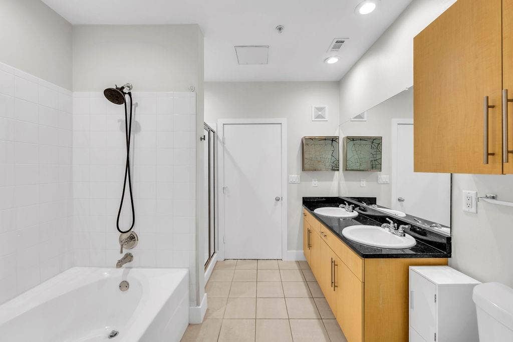 4605 Cedar Springs Road, #327, Dallas, TX 75219 White tile tub and shower combination with a handheld showerhead
