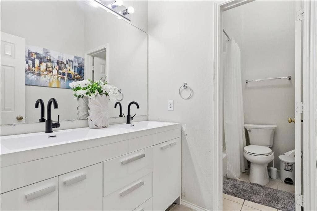 Dual vanity with integrated sinks, matte black faucets, and a full-width mirror