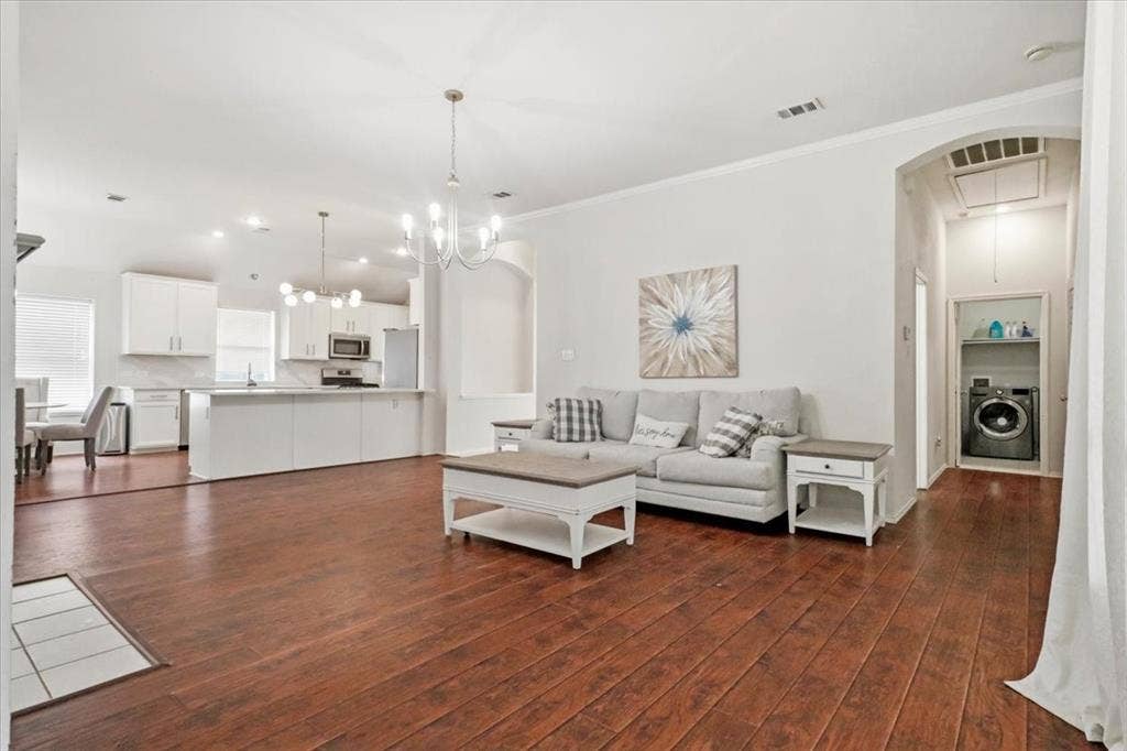 Expansive wood-finish flooring, recessed lighting, and a modern chandelier
