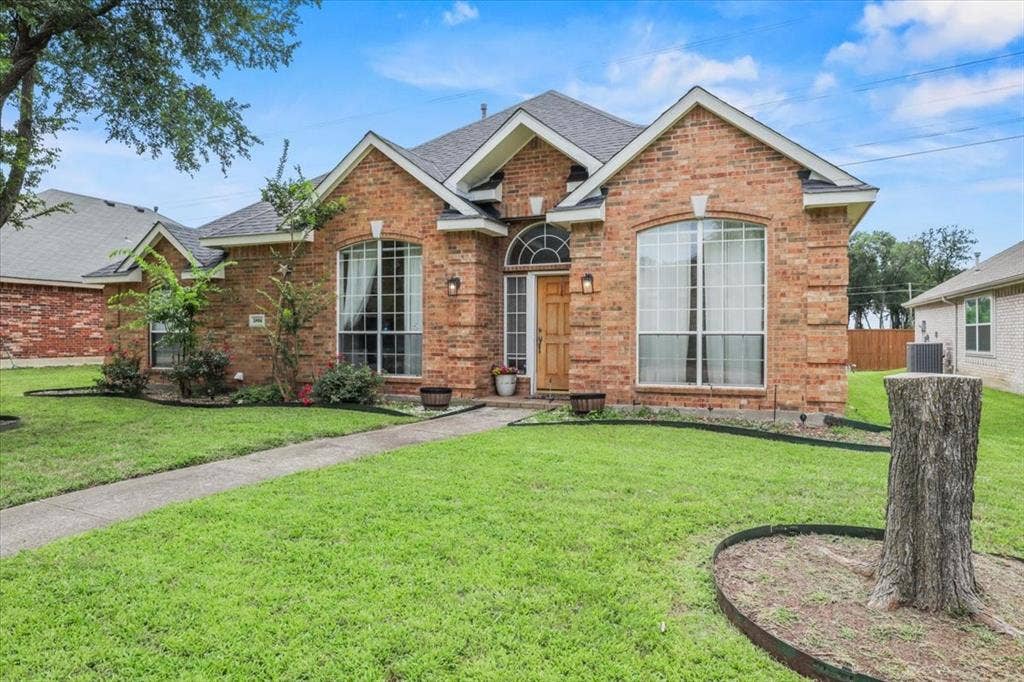 Brick exterior with arched windows, prominent gables, and a wood-finish entry door