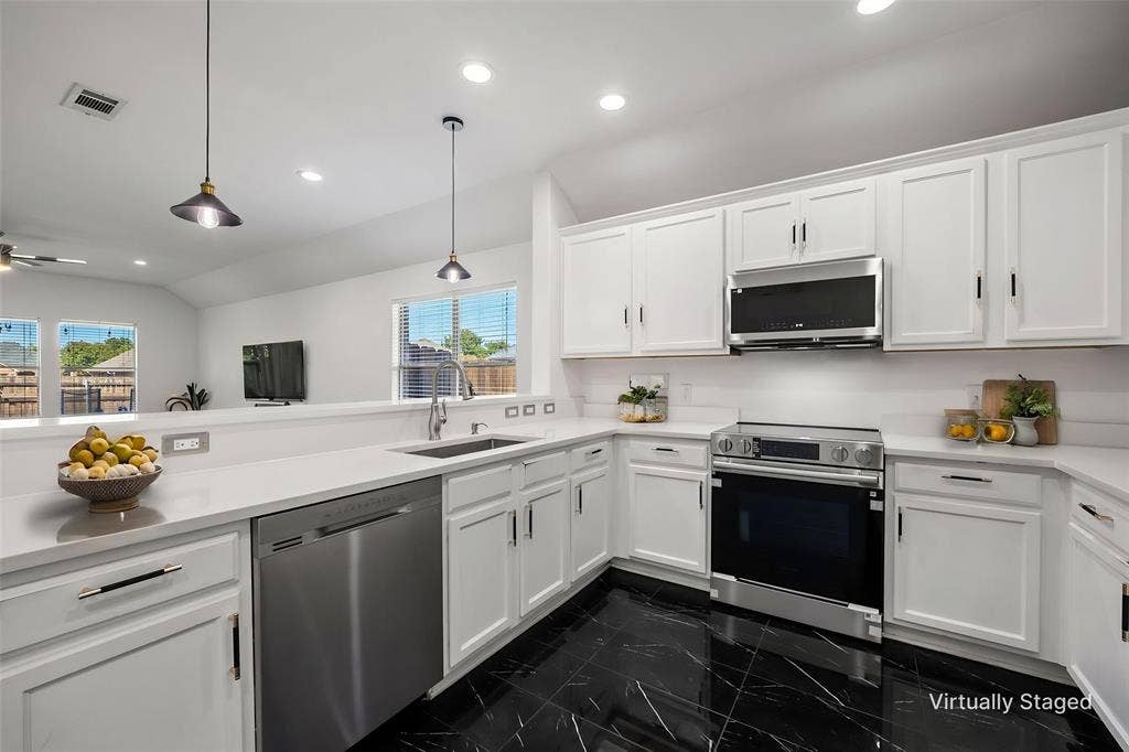 221 Cliffbrook Drive, Wylie, TX 75098 White cabinetry, stainless steel appliances, black tile flooring, recessed lighting, and a kitchen peninsula with pendant lighting