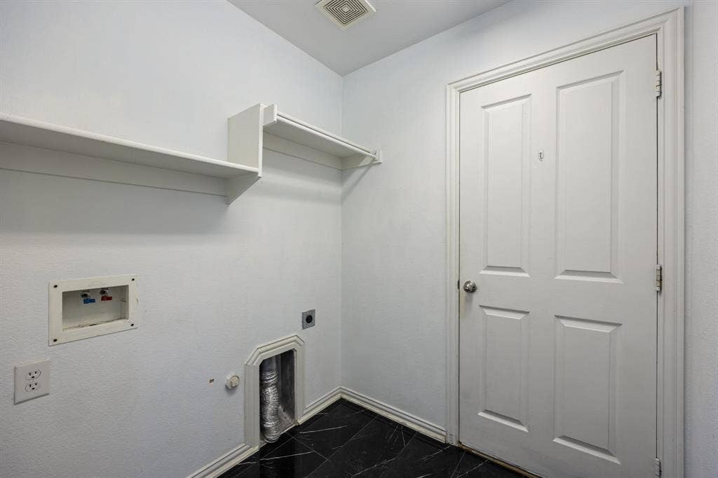 221 Cliffbrook Drive, Wylie, TX 75098 Laundry area featuring built-in shelving, a panel door, black tile flooring, and utility hookups
