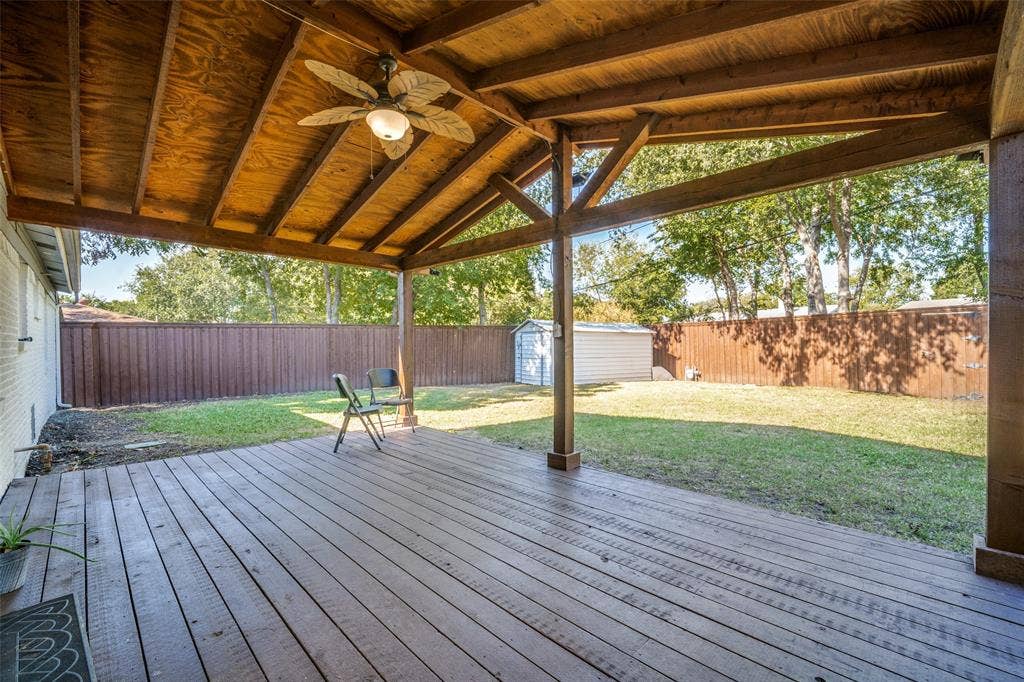 3209 Karla Drive, Mesquite, TX 75150 Expansive covered wood deck with a ceiling fan, overlooking a fenced backyard with a detached storage shed