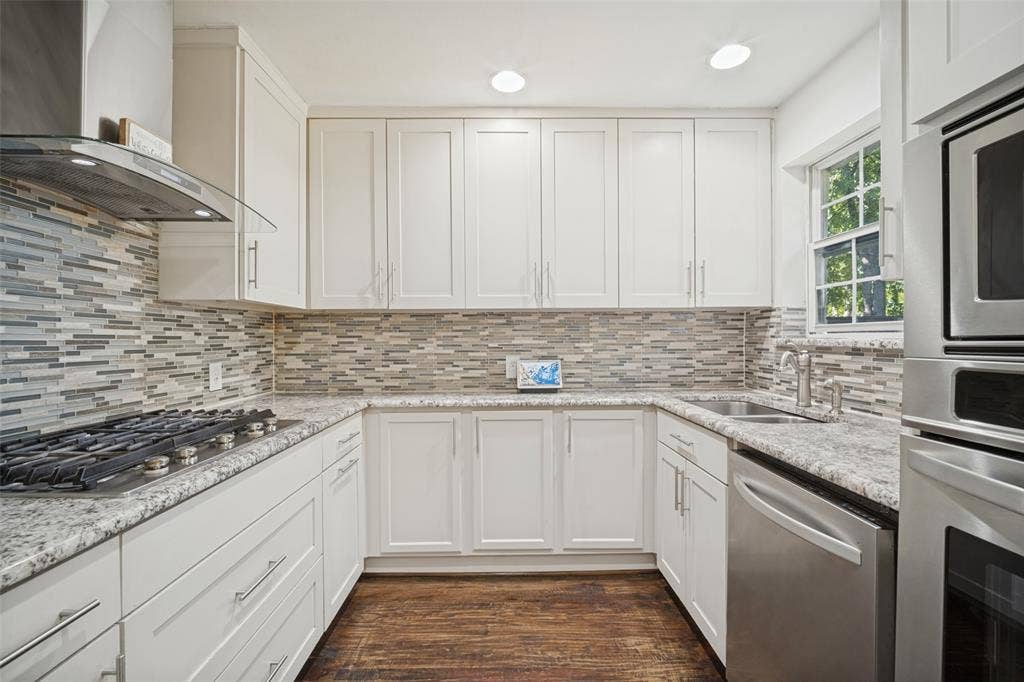 3209 Karla Drive, Mesquite, TX 75150 Modern kitchen featuring white cabinetry, stainless steel appliances, a tile backsplash, light-toned countertops, and wood-finish flooring