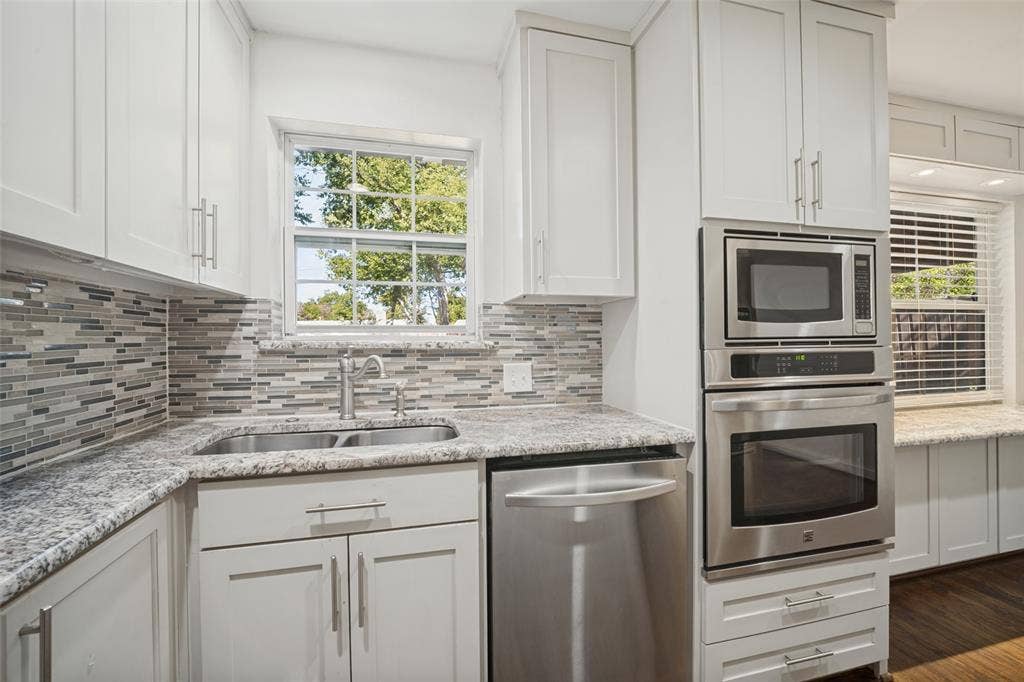 3209 Karla Drive, Mesquite, TX 75150 White cabinetry, stainless steel appliances, mosaic tile backsplash, double basin sink, and ample countertop space