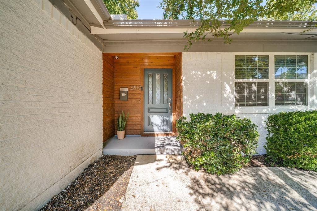 3209 Karla Drive, Mesquite, TX 75150 White brick exterior with a wood-paneled entry