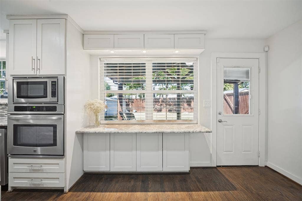 3209 Karla Drive, Mesquite, TX 75150 Integrated stainless steel microwave and oven, white cabinetry, light-toned countertop, wood-finish flooring, and a glass-paneled exterior door