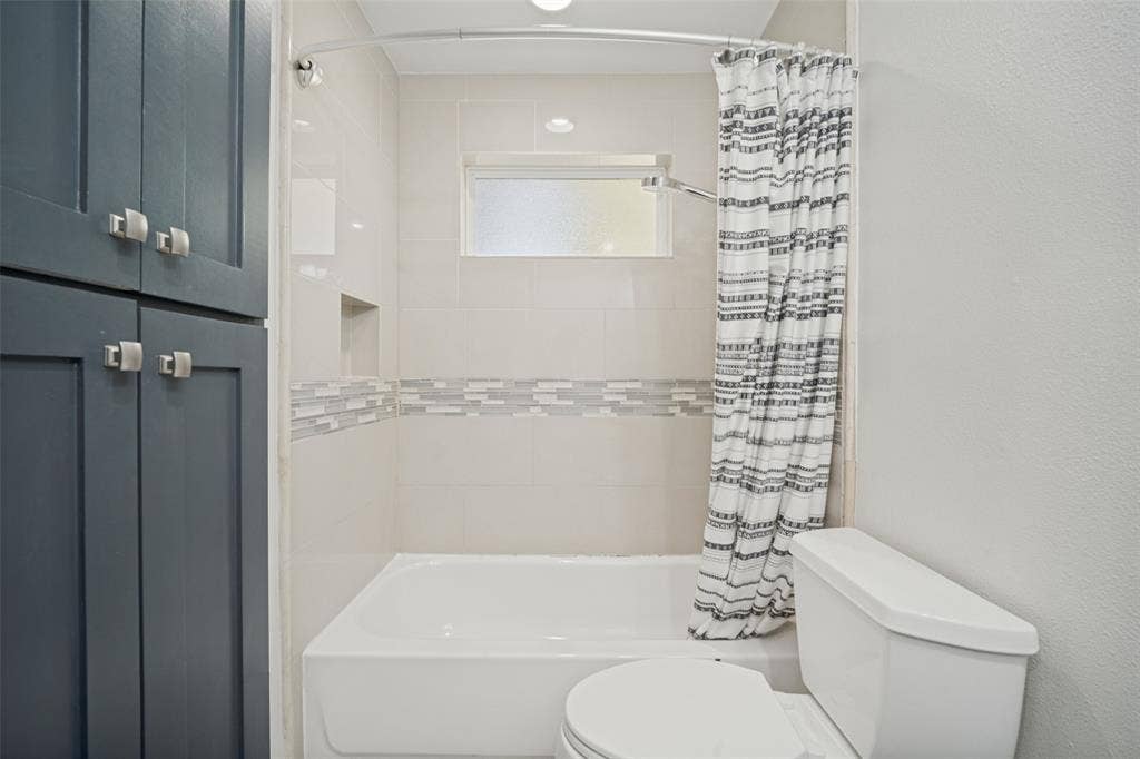 3209 Karla Drive, Mesquite, TX 75150 Built-in cabinetry with square pulls, fully tiled shower with accent band, recessed shower niche, frosted window, and recessed lighting
