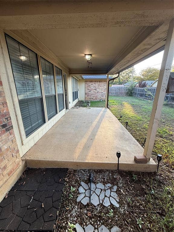 3407 Ruidoso Drive, Arlington, TX 76017 Covered concrete patio with overhead lighting, brick exterior, and a fenced backyard