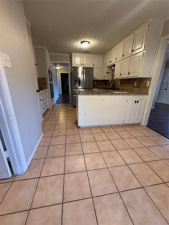3407 Ruidoso Drive, Arlington, TX 76017 Ceramic tile flooring, white cabinetry, stainless steel refrigerator, built-in ovens, and a tiled backsplash