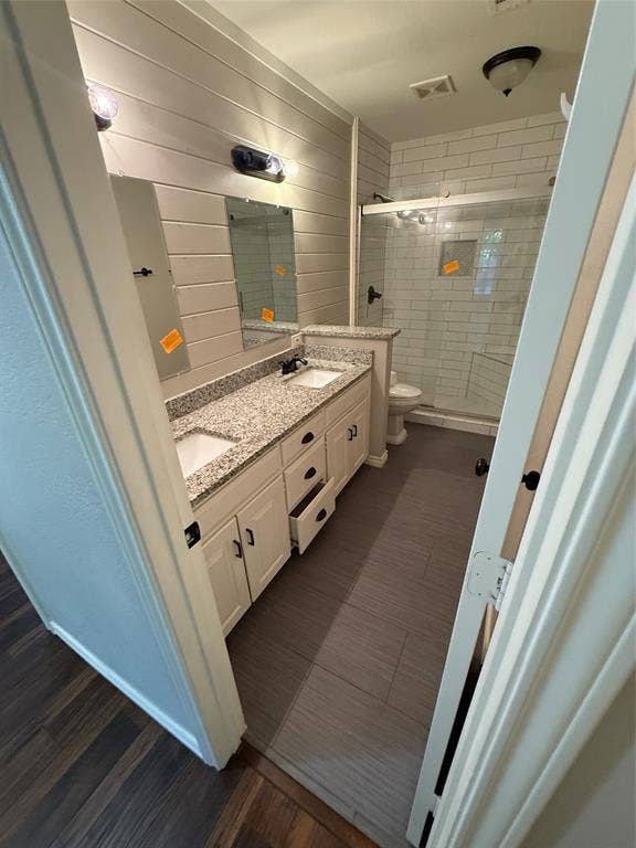 3407 Ruidoso Drive, Arlington, TX 76017 Dual vanity with granite-style countertop and integrated sinks, complemented by shiplap wall paneling and rectangular mirrors
