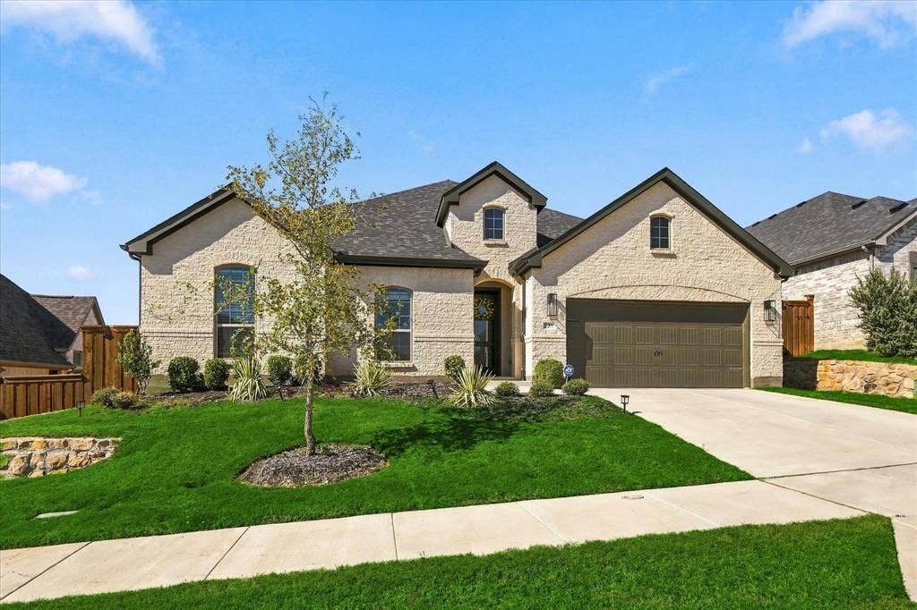Stucco exterior featuring arched entryways, a two-car garage, and a concrete driveway