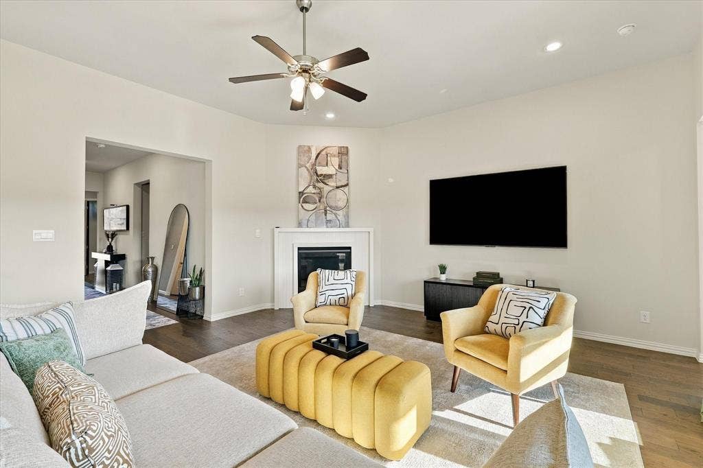 Spacious living area featuring wood-finish flooring, a ceiling fan, recessed lighting, and a built-in fireplace with a mantel