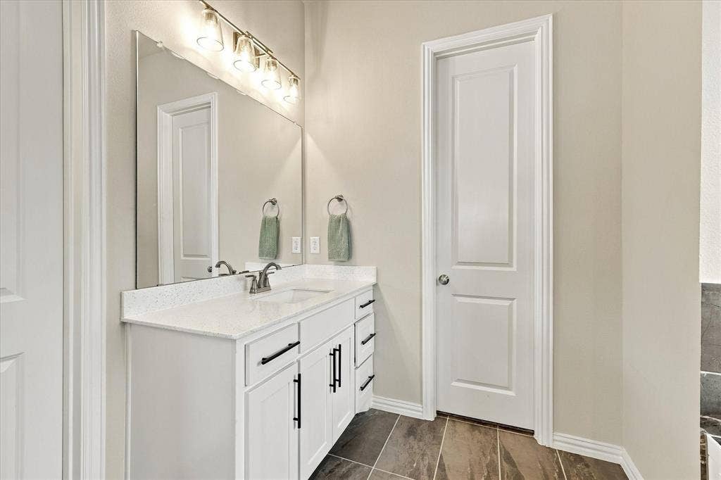 Vanity with white cabinetry, a single basin sink, and a light-colored countertop