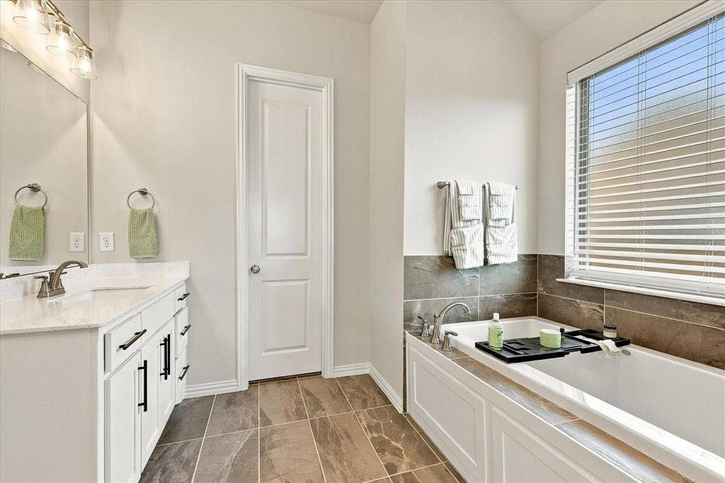 White vanity with a light-colored countertop, undermount sink, and bronze-finish faucet