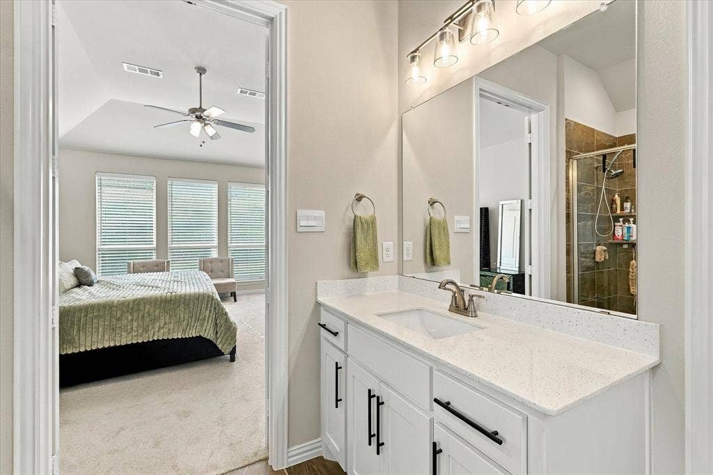 Vanity with a white countertop and integrated sink, complemented by a large wall-mounted mirror and brushed nickel fixtures