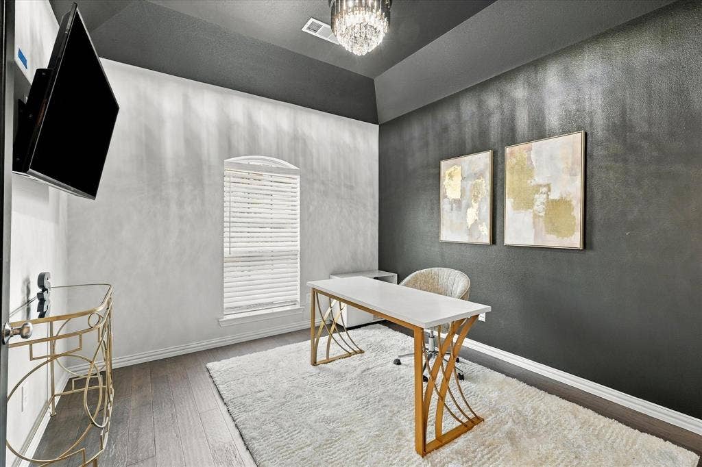 Tray ceiling with a crystal chandelier, wood-finish flooring, and arched window with blinds